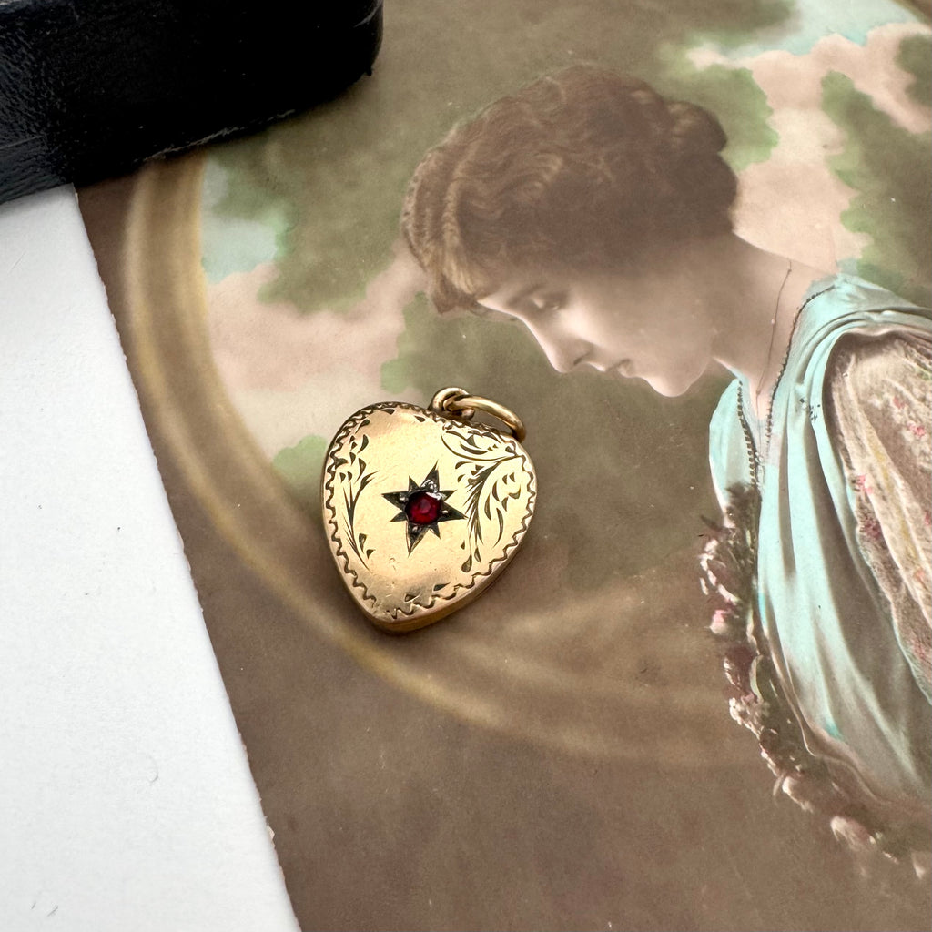 Vintage heart-shaped locket with a red stone on an old photograph of a woman.