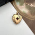 Vintage gold  heart-shaped locket  with a red stone on a white surface