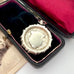 Vintage 1937 Chester silver watch fob on a white surface next to an open box with velvet interior.