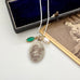 Necklace with pendant and green stone on a white surface with an old photograph in the background
