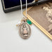 Necklace with a pendant labeled 'Infant of Prague' on a white surface with an old photograph in the background.
