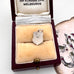 Jewelry box with a vintage silver charm featuring a coat of arms and 'MACKENZIE' text on a white background.