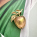 Rare GB stamped Sarah Coventry gold apple-shaped brooch with leaves on a green and white fabric background