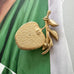 Rare GB stamped Sarah Coventry gold apple-shaped brooch with leaves on a green and white fabric background