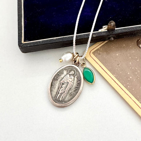 Vintage St Paul silver pendant, green gemstone, and pearl necklace on a white surface.
