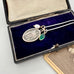 Necklace with a vintage St Paul silver pendant, green gemstone, and pearl in an open jewelry box.