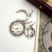 A vintage silver horseshoe charm, no 13 charm and a 1918 British threepence on a white background with an old postcard in the corner.