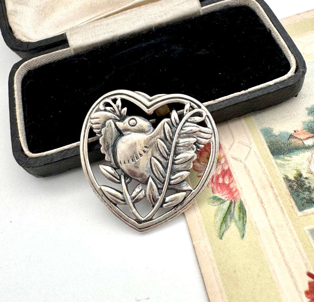 Silver heart-shaped pendant with bird design in a black box