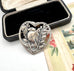 Silver heart-shaped pendant with bird design in a black box