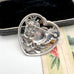 Silver brooch with a design on a textured surface