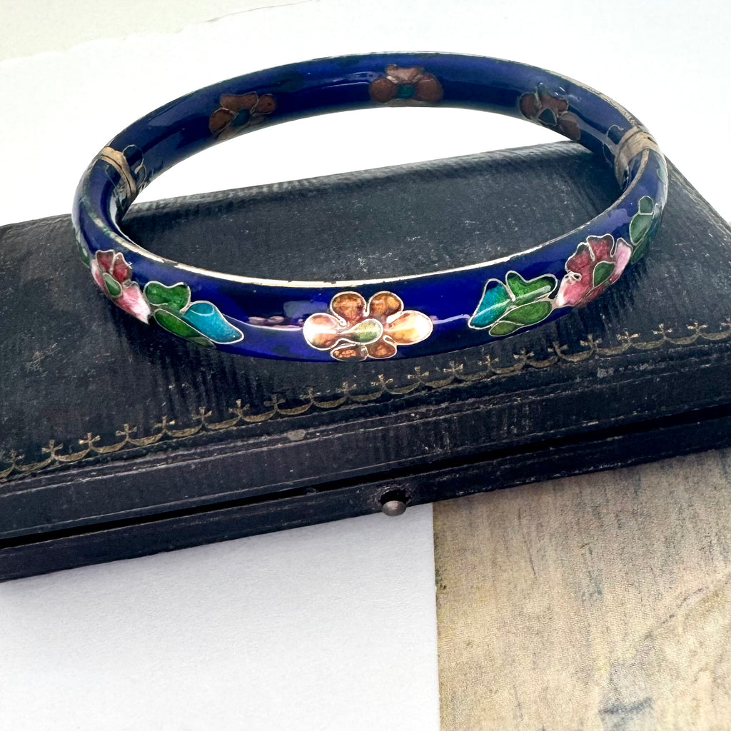 Decorative blue cloisonee bangle with floral patterns on a black background
