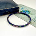 Blue cloisonne bangle on an old jewellery box and with a postcard with floral design