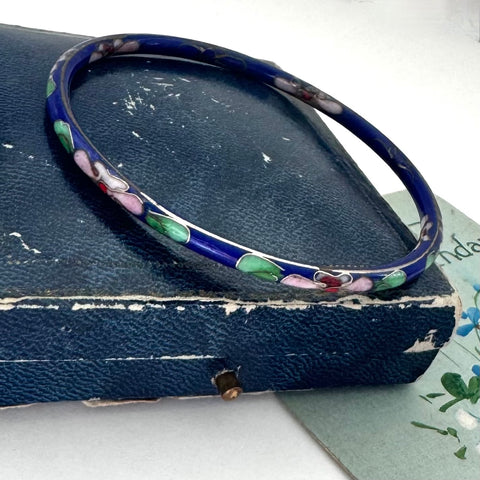 Blue cloisonne bangle on an old jewellery box and with a postcard with floral design
