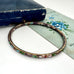Vintage taupe cloisonne bangle on an old floral postcard and jewellery box