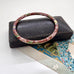 Vintage brown cloisonne bangle on an old jewellery box and vintage Christmas postcard.
