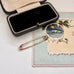 Gold safety pin on a textured surface with a decorative card in the background