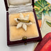 Back of vintage daffodil brooch in a jewelry box with vintage cards in the background
