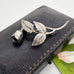 Vintage Danish John Lauritzen silver leaf and rose brooch on a textured black surface