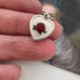 Vintage enamel guilloche heart and St Christopher charm on an old masters portrait of a woman and in a woman's hand