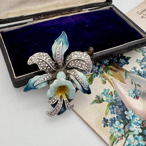 Vintage enamel and marcasite orchid brooch on a vintage postcard and jewellery box