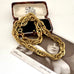 A chunky French vintage rolled gold chain necklace draped over an open vintage jewelry box, with a black-and-white portrait card underneath on a light surface.