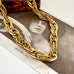 A chunky French vintage rolled gold chain necklace with thick, textured interlocking links, draped over a vintage black-and-white print featuring the name 'ASTA NIELSEN'.