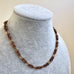 A close-up of a Jakob Bengel Byzantine link necklace displayed on a light gray fabric jewelry bust against a plain beige background.