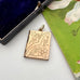 Gold engraved locket on a white surface with a floral card and black box in the background