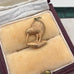 Gold kiwi bird pendant on a soft, textured surface