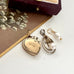 Vintage gold heart-shaped locket, pearl pendant and pearl on a white surface.