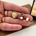 Gold heart-shaped pendant, teardrop-shaped pendant with pearl, and small gold pendant with pearl held in a hand.