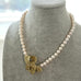 Pearl necklace with a gold pendant on a gray bust