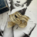 Vintage gold tone bow brooch with geometric design on a black and white background