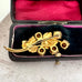 Back of vintage brooch on an open jewelry box on a textured surface