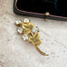 Gold brooch with leaves and crystals on a textured surface