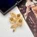 Gold floral brooch on a white surface with an old photograph in the background