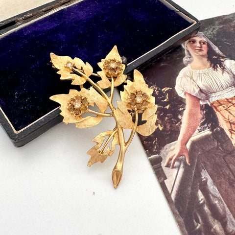 Vintage gold tone floral brooch with a vintage-style portrait in the background