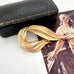 Sarah Coventry vintage gold brooch on a white surface with an old photograph in the background