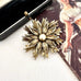 Vintage signed Hollywood gold tone flower brooch on an old jewellery box and with a vintage postcard