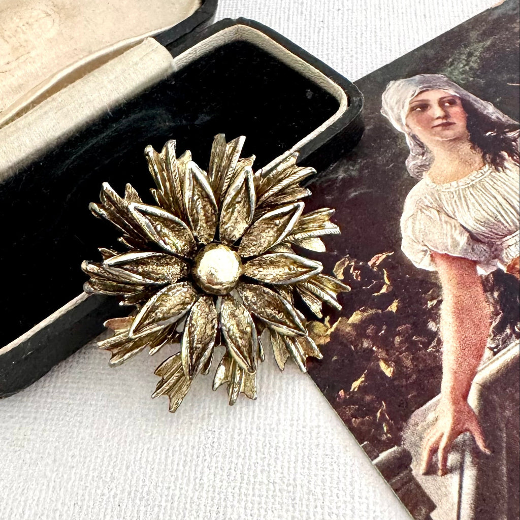 Vintage signed Hollywood gold tone flower brooch on an old jewellery box and with a vintage postcard