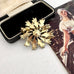 Back of vintage signed Hollywood gold tone flower brooch on an old jewellery box and with a vintage postcard