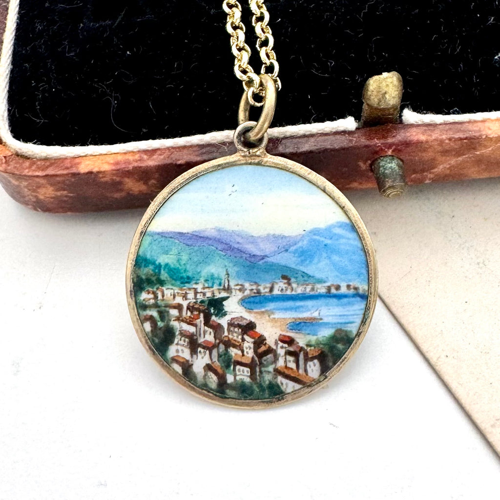 Vintage hand painted scene of Rapallo on the Italian riviera. A pendant on a chain leaning on an old jewellery box.