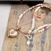vintage heart locket and pearl and peruvian opal necklace on an open jewellery box and with a vintage postcard.