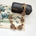 Vintage micro mosaic bracelet with floral designs in a jewelry box on a floral vintage postcard.