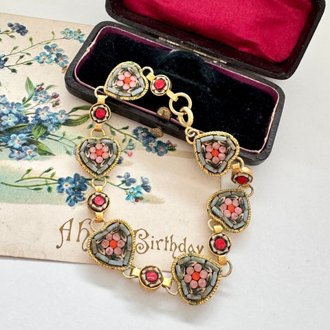 Vintage micro mosaic bracelet with floral designs in a jewelry box on a floral vintage postcard.