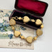 Back of vintage micro mosaic bracelet with floral designs in a jewelry box on a floral vintage postcard.