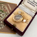 Gold jewelry set with a locket and pearl pendant in an open jewelry box.