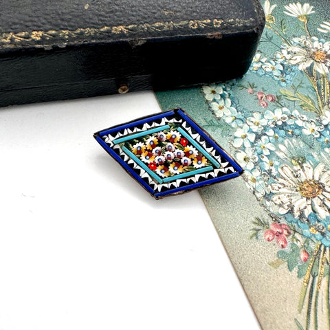 Vintage micro mosaic brooch on a floral-patterned fabric background