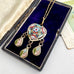 A vintage gold-tone micro mosaic pendant necklace with matching drop earrings, featuring colorful enamel inlay, displayed inside an open dark velvet jewelry box.