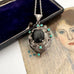 Vintage art nouveau mid century revival necklace with black stone and turquoise stones on a textured surface